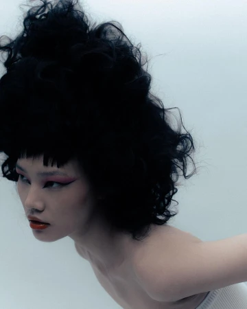 Portrait of a model with voluminous dark curly hair, pink winged eyeliner, and red lipstick by Vanessa Granda