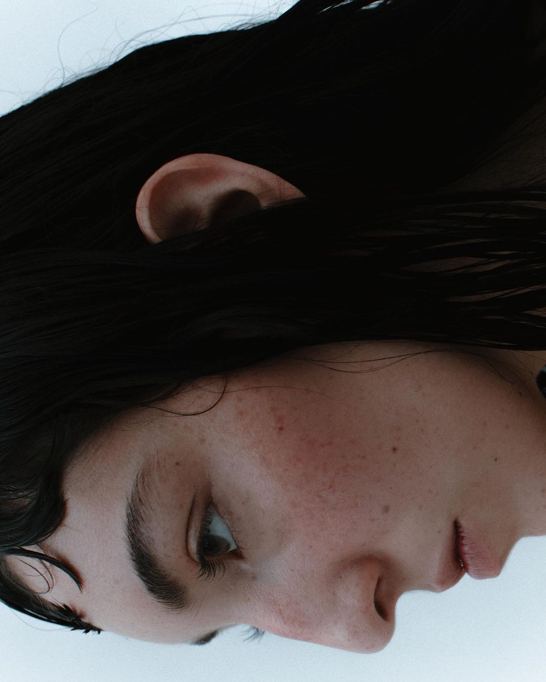 Close-up profile portrait of a person with dark wet hair and freckles by photographer Vanessa Granda