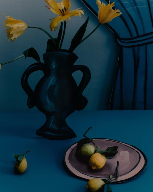 Still life of yellow tulips in a black vase, lemons on a plate and scattered on a blue table against a striped blue curtain.