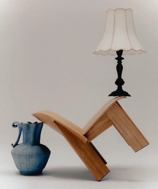 Still life of wooden chair, blue ceramic vase, and white lampshade against a neutral backdrop in a photo studio.