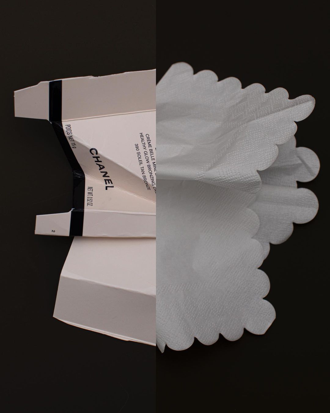 Chanel skincare product in open white packaging, alongside a white frilly tissue, presented on a dark surface. Product photography.