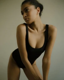Woman in a black bodysuit posing against a neutral background photographed by Vanessa Granda.