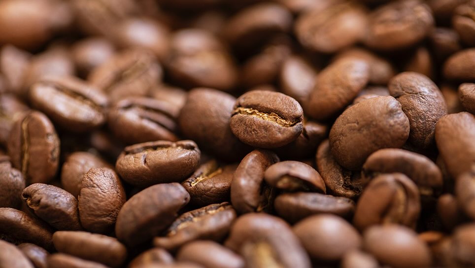 Close-up of coffee beans with a shallow depth of field showing various shades of brown. Food and beverage background.