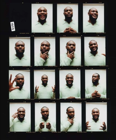 Contact sheet of adult male with a slight smile wearing a light green sweater, in a photo studio with white background and dark framing.