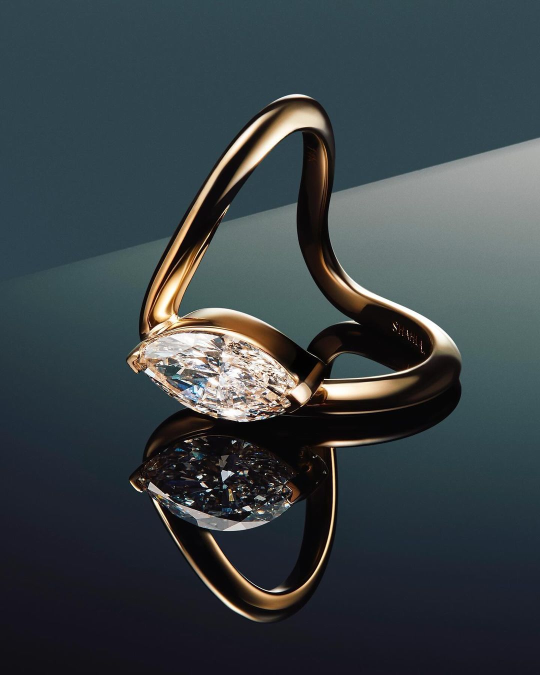 Elegant gold ring with a large, sparkling marquise-cut diamond on a reflective surface, studio lighting, showcasing luxury jewelry.