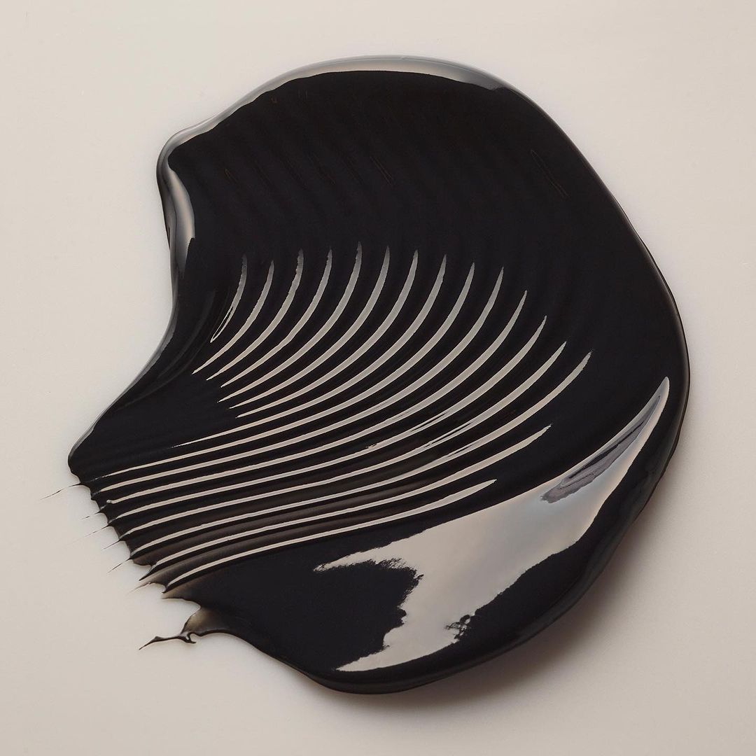 Swirl of black cream with visible lines. Beauty shot of cosmetic or skincare product on a clean, light background.