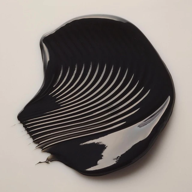 Swirl of black cream with visible lines. Beauty shot of cosmetic or skincare product on a clean, light background.