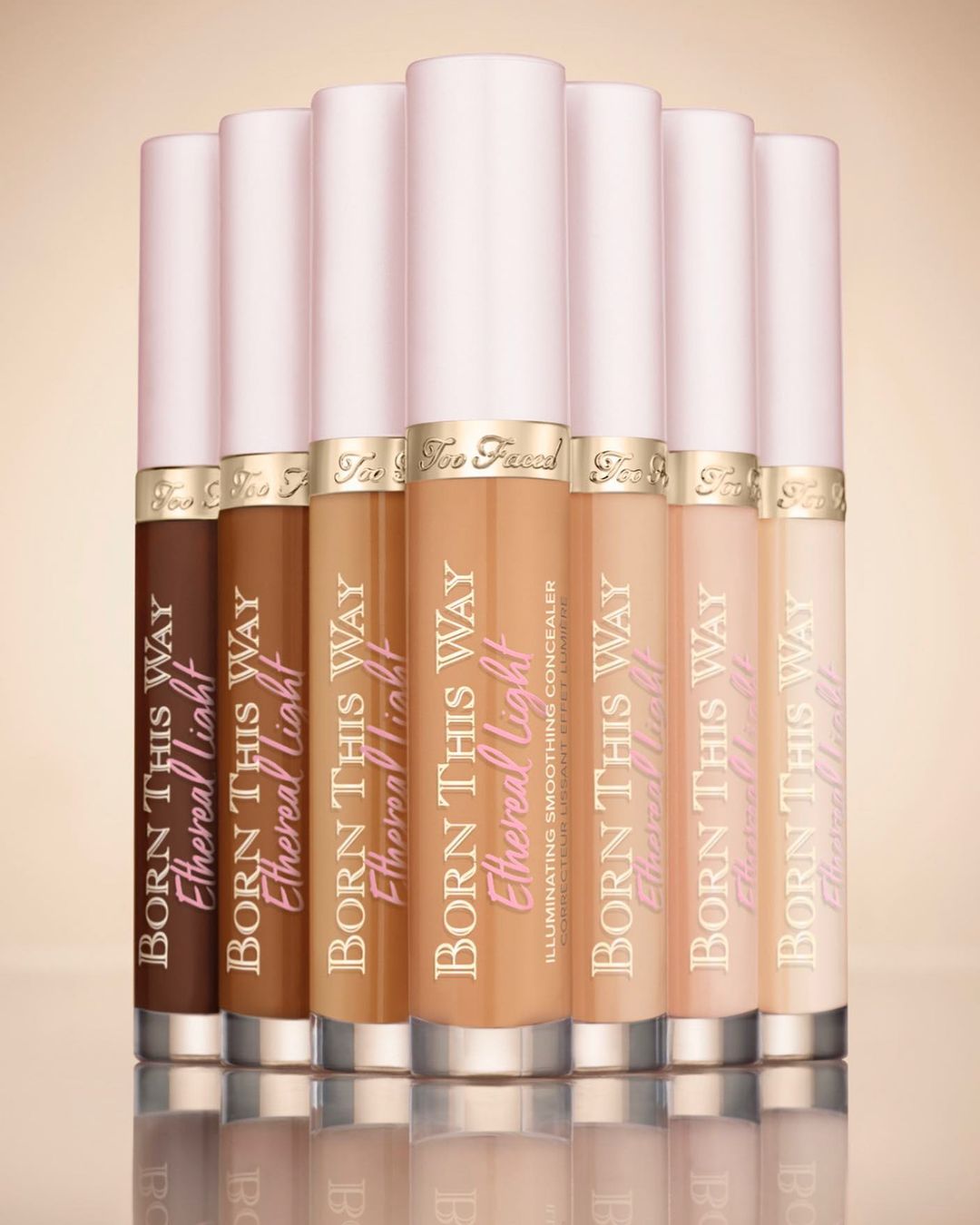 Assortment of 'Born This Way Ethereal Light' concealer tubes in various skin tones, lined up against a neutral background, beauty product.