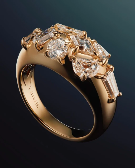 Elevated view of an ornate gold ring set with various cut diamonds against a deep teal backdrop in a jewelry product shot.