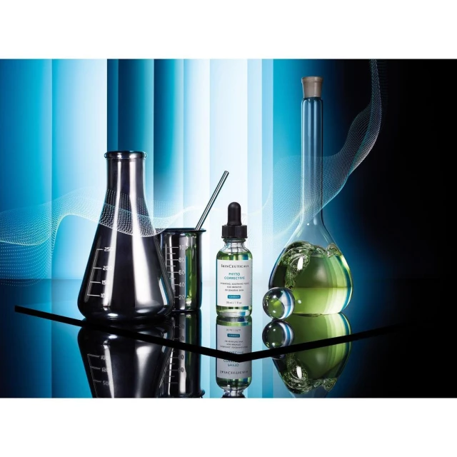 Cosmetic product photography featuring SkinCeuticals Phyto Corrective serum with scientific glassware and cool blue lighting on a reflective surface.