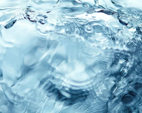 Abstract close-up of flowing water, with light reflections and a clear, fresh appearance, creating a dynamic visual texture.
