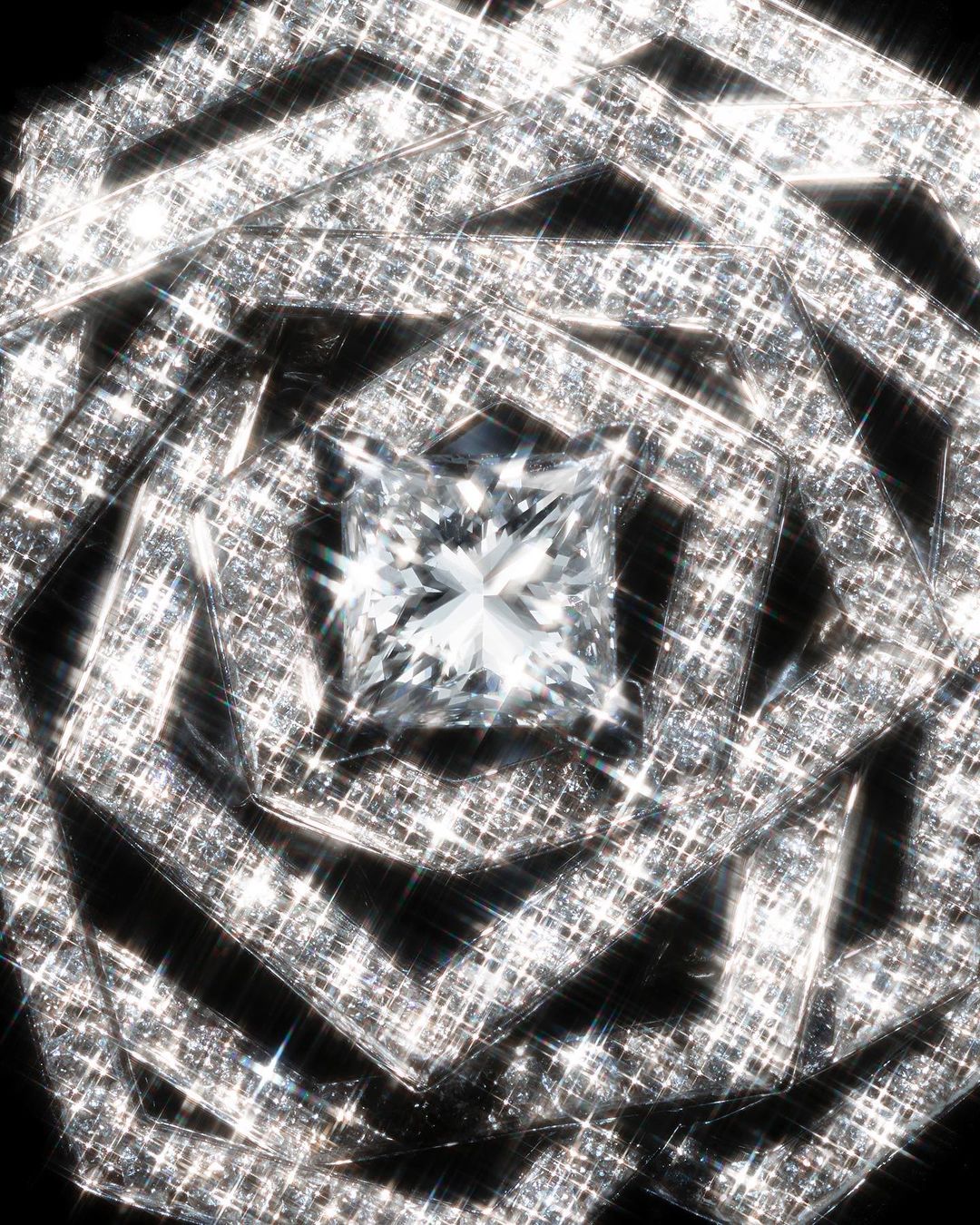 Close-up of a large, square cut diamond with multiple square frames around it, glittering against a black background.