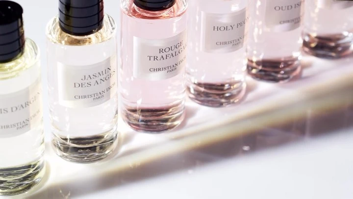 Close-up of clear glass perfume bottles with black caps, arranged in a row on a white surface, featuring Christian Dior brand labels.