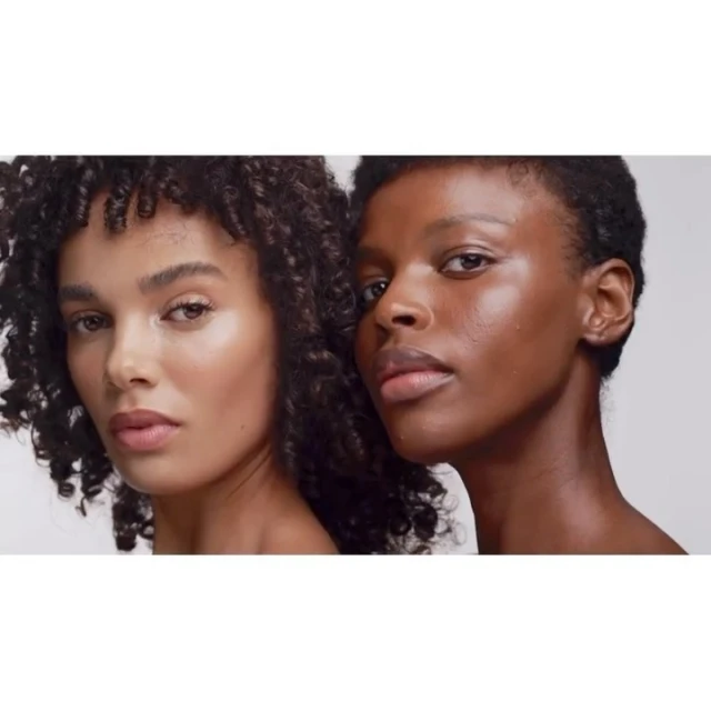 Two women with curly hair pose in a close-up shot. One model has lighter skin and curly hair, while the other model has darker skin.