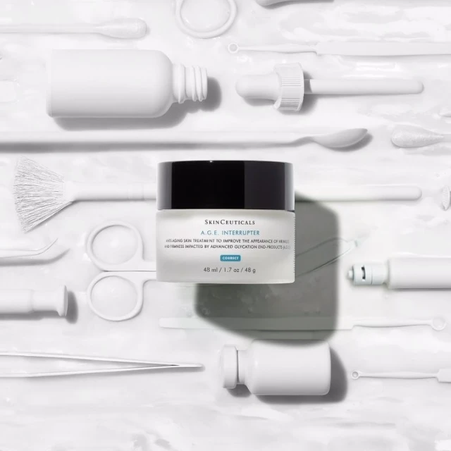 Skinceuticals A.G.E. Interrupter cream jar surrounded by skincare tools, all in a bright, clean, and minimalist product shot.