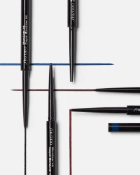 Black eyeliner pencils arranged vertically and horizontally with precise colored ink swatches on a clean white background.