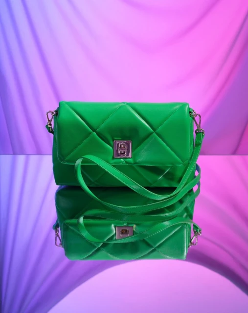 Bright green quilted purse on a reflective surface with an abstract pink and purple backdrop, fashion accessory, studio product shot.