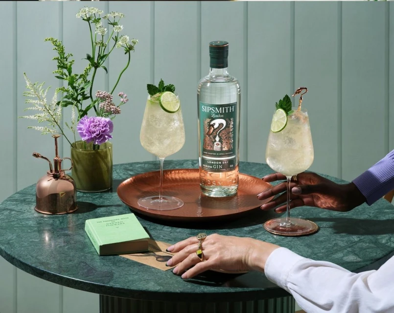 Sipsmith gin bottle and cocktails on a marble table, presented by two people and decorated with flowers, showcasing an elegant presentation.