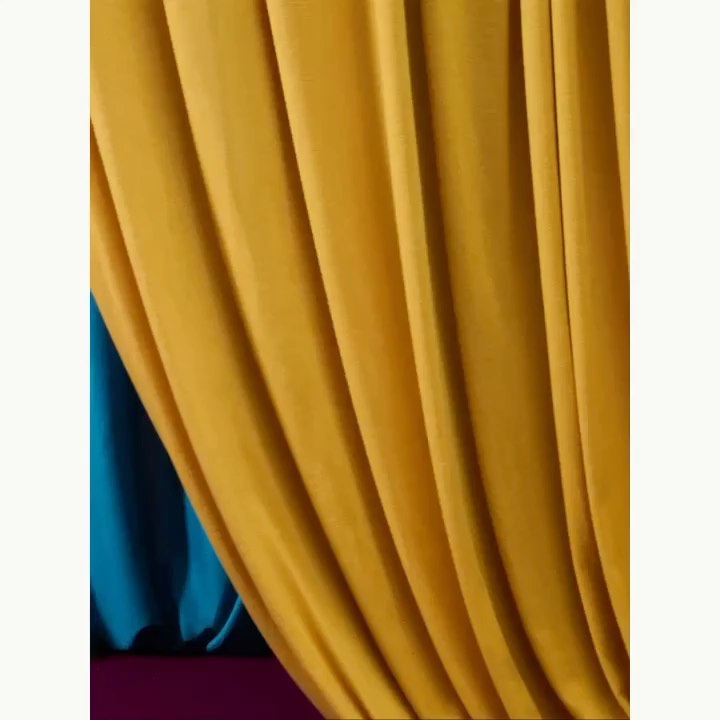 Close-up of folded yellow fabric with blue and purple accents, creating a visually striking and textured abstract composition.