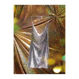 Silver chainmail halter dress hanging on a wire hanger against a shimmering bronze holographic background.
