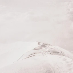 Aerial view of a snowy mountain ridge under an overcast sky by Vincent Bousserez in Paris