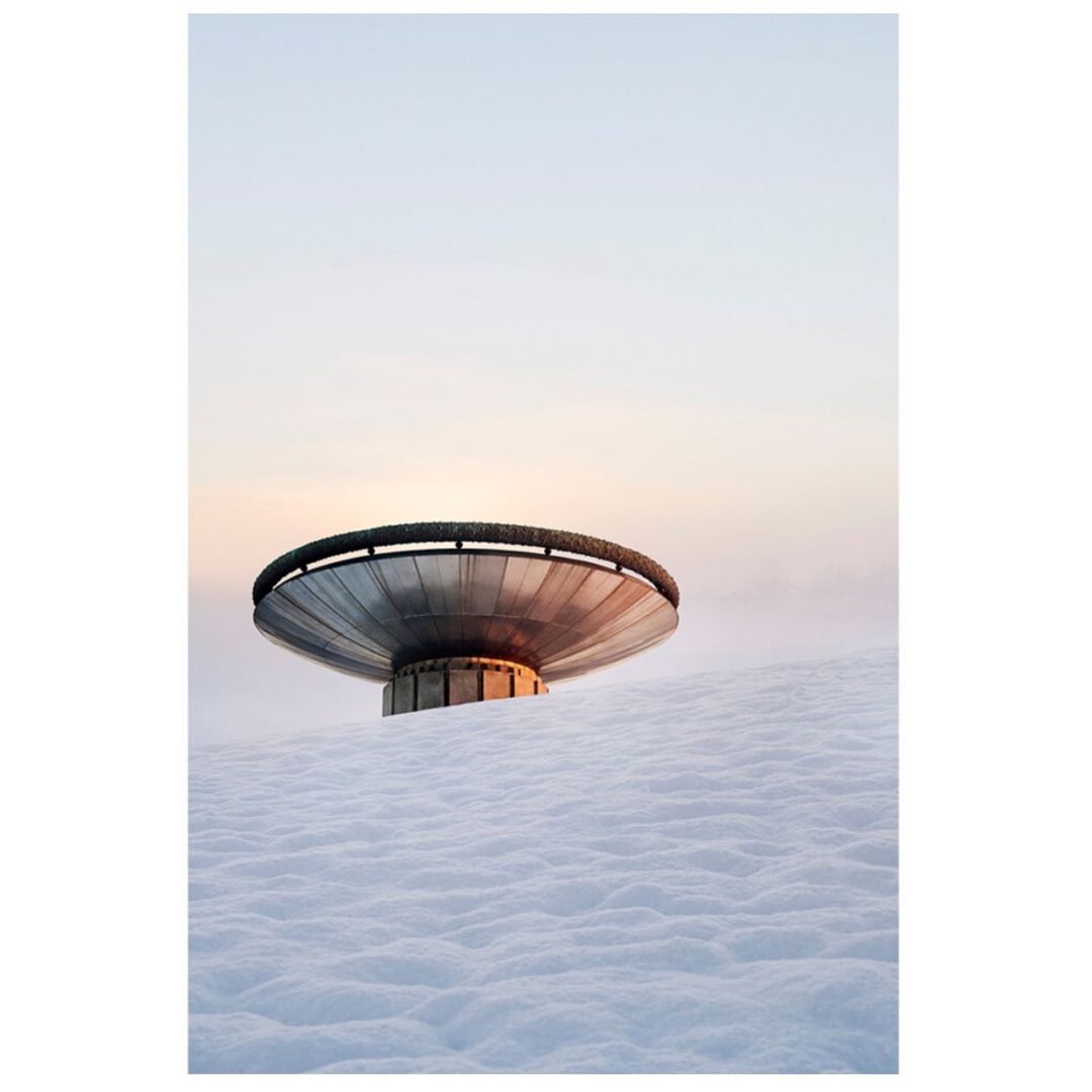 Snowy landscape featuring a large metal structure under a pastel sky, reflecting light. Minimalist composition with focus on texture and form.
