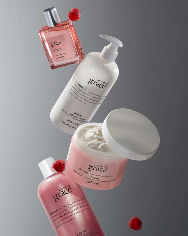 Cosmetic product bottles and jars arranged on a gray surface, raspberries accent the items, promoting beauty and self-care.