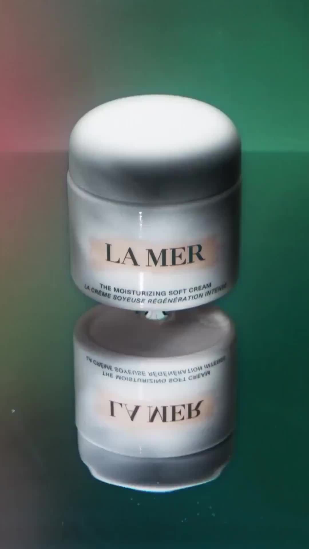 La Mer moisturizing soft cream jar on a reflective surface with a colorful background, product photography, beauty and skincare.