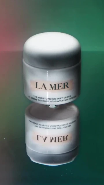 La Mer moisturizing soft cream jar on a reflective surface with a colorful background, product photography, beauty and skincare.