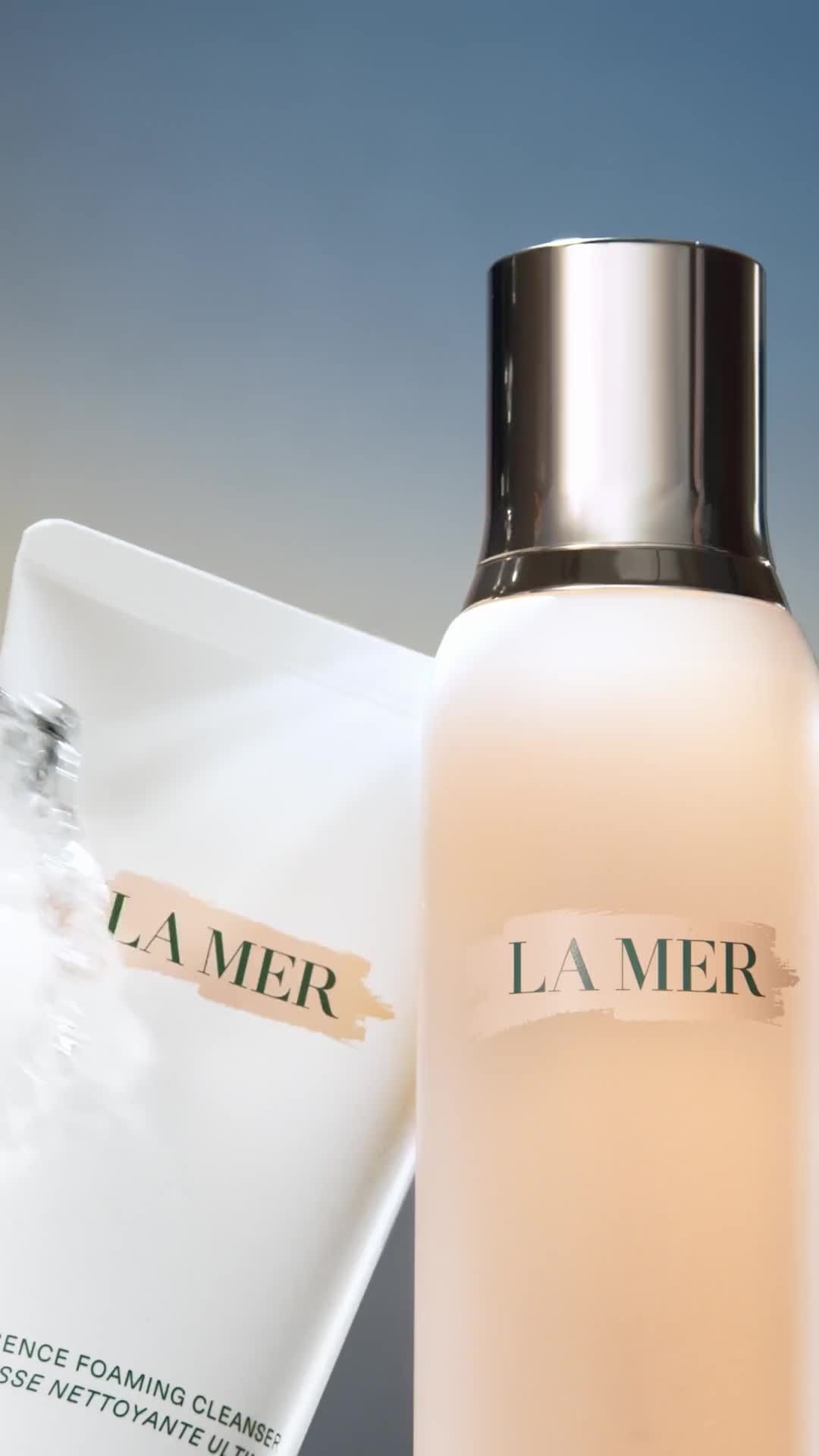 La Mer skincare products on display: cleanser in white packaging and moisturizing cream in light pink bottle with silver cap.