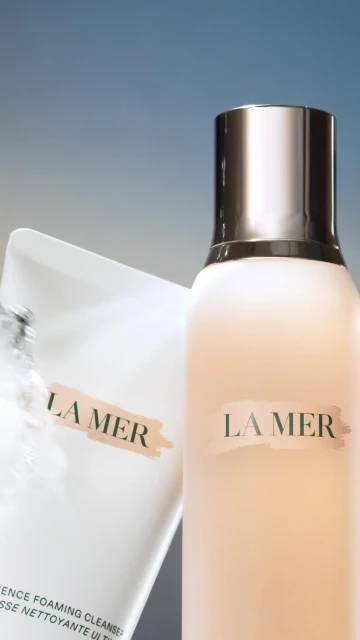 La Mer skincare products on display: cleanser in white packaging and moisturizing cream in light pink bottle with silver cap.