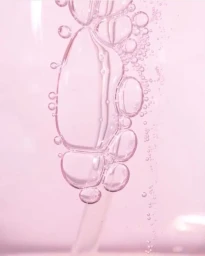 Macro view of transparent bubbles clustered in pink liquid with soft monochromatic lighting and smooth textures.