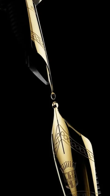Close-up studio shot of two gold and black fountain pen nibs, one suspended above the other with a droplet between them on a black background.