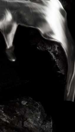 Abstract close-up of textured, rippled rock formation with silver and grey tones against a contrasting black background.