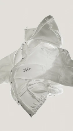 White puffer jacket suspended in mid-air against a plain off-white background captured in Paris
