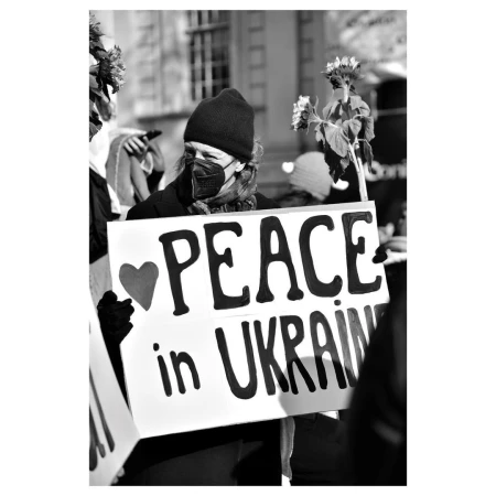 Black and white portrait of a person holding a sign with the words 'Peace in Ukraine' written on it, with a heart symbol.