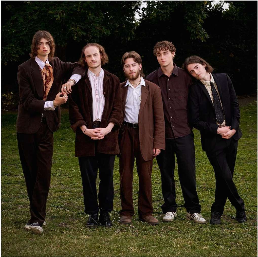 Five young men in vintage tailoring standing outdoors on a grassy lawn photographed by Virginie Khateeb.