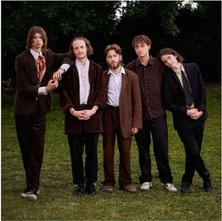 Five young men in vintage tailoring standing outdoors on a grassy lawn photographed by Virginie Khateeb.