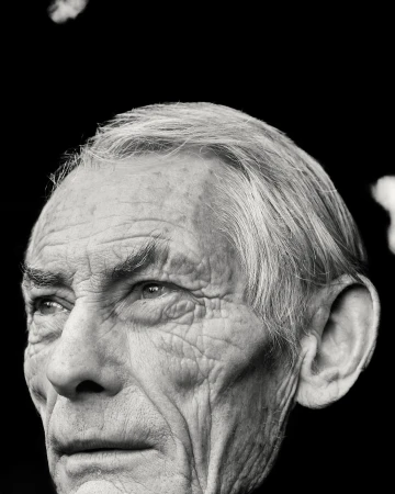 Monochrome portrait of an elderly man with detailed facial features, showcasing a close-up of his face against a dark background.