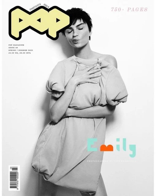 Fashion magazine cover featuring an adult female model wearing a short grey dress, close-up shot, white background, minimalist composition.