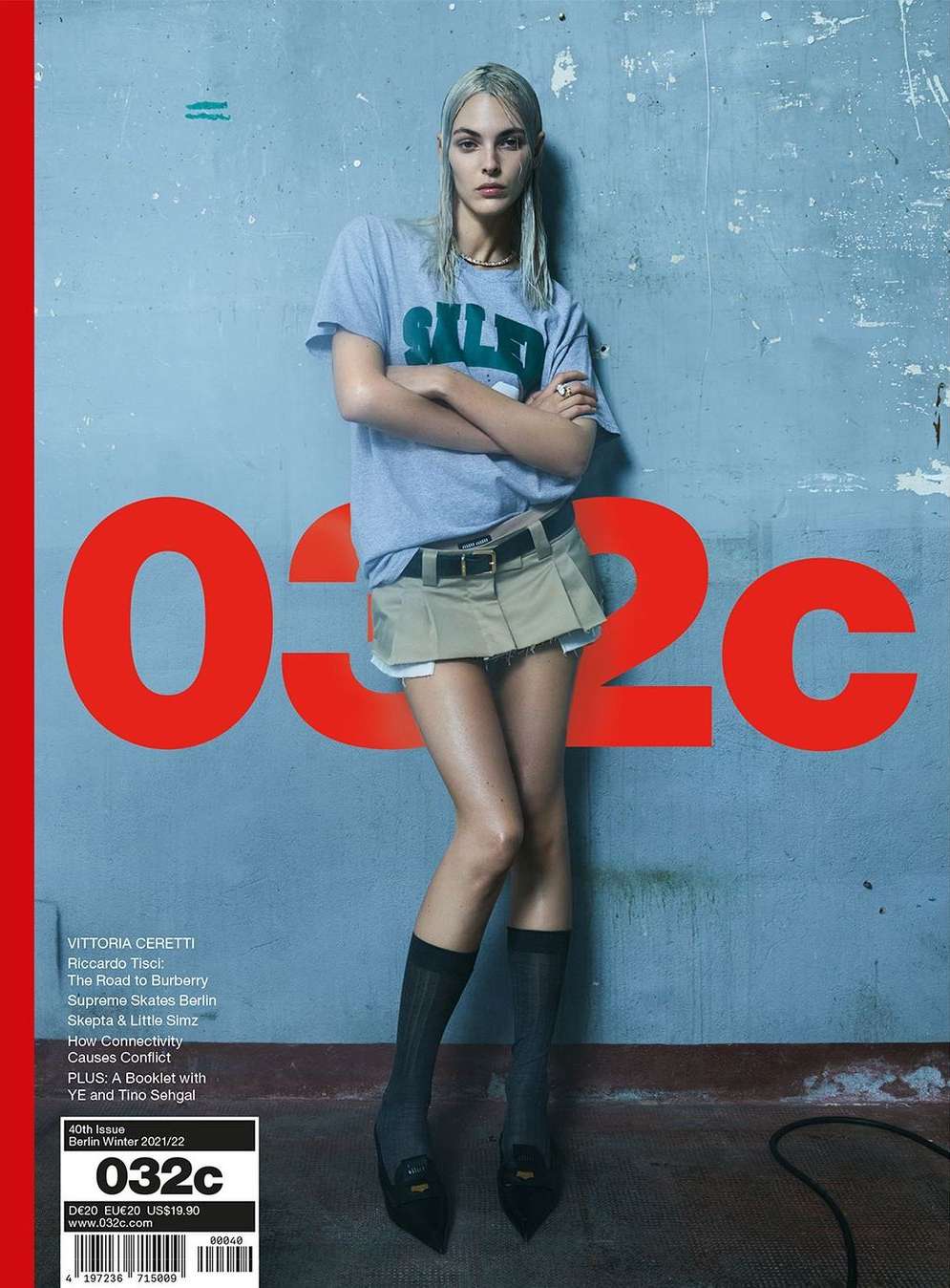 Magazine cover featuring a model wearing a gray t-shirt and khaki skirt against a blue background with large red magazine title text.
