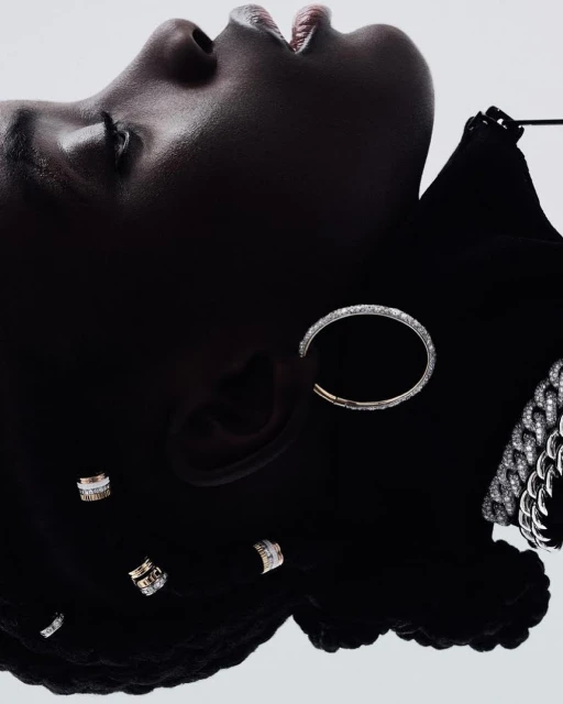 Close-up of a dark-skinned woman wearing silver and diamond earrings and a necklace while lying on her back in a studio.