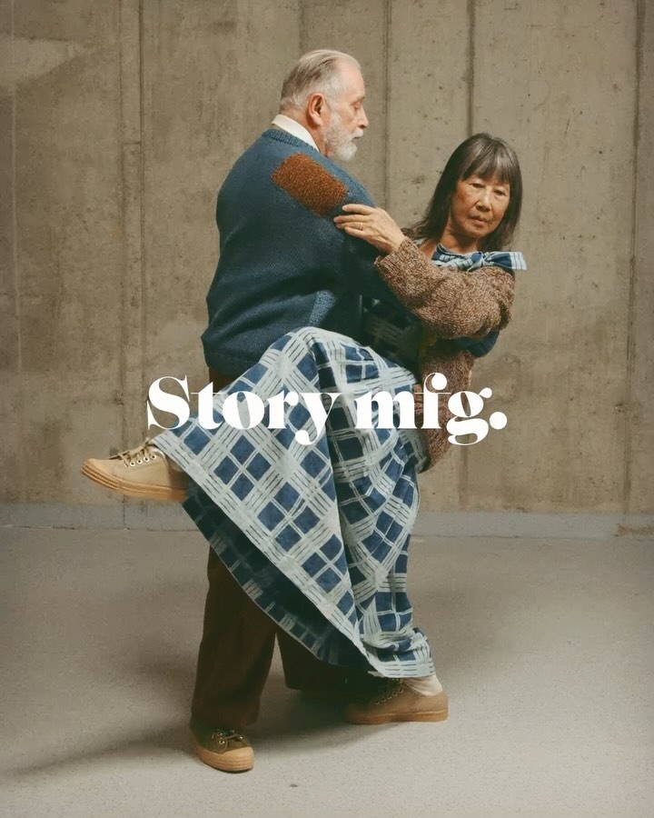 Elderly couple in casual wear in an embrace indoors in front of a concrete wall with neutral, soft lighting and visual brand text.