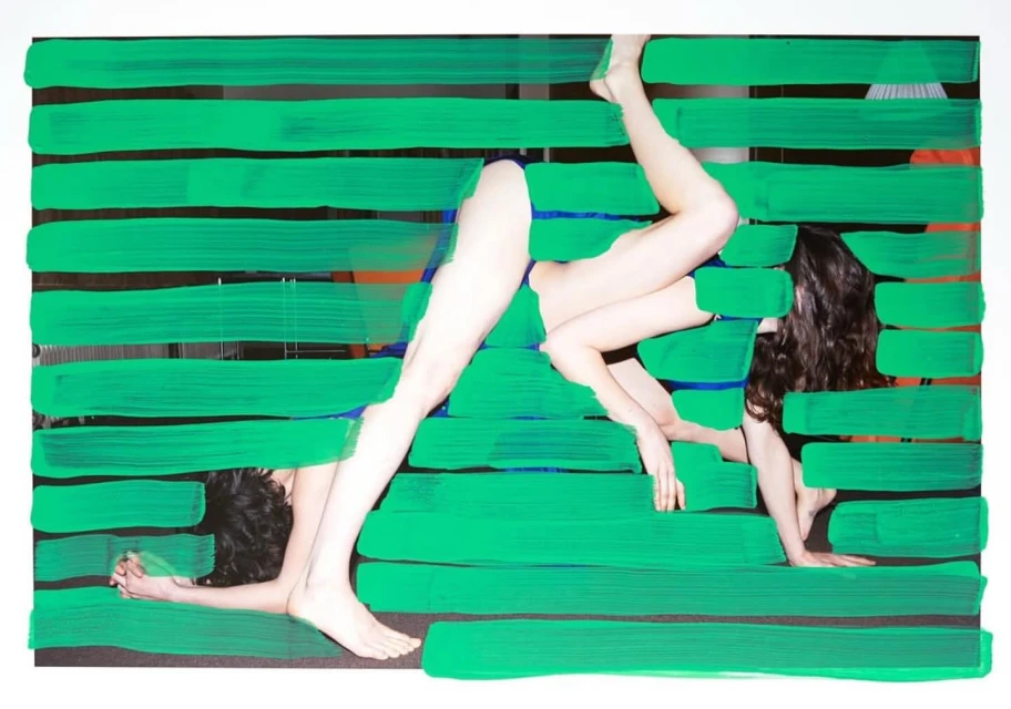 Abstract composition featuring two women lying behind green horizontal bars, creating an artistic and visually intriguing pattern.