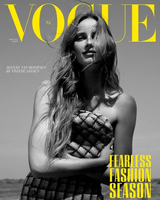 Vogue NL cover featuring a woman with long hair, wearing a checkered pattern outfit, in an outdoor setting against a bright sky.