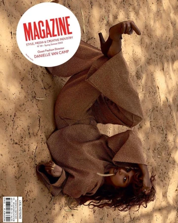 Model lying on sandy ground wearing a metallic brown trouser suit with high heels, photographed by Viviane Sassen.