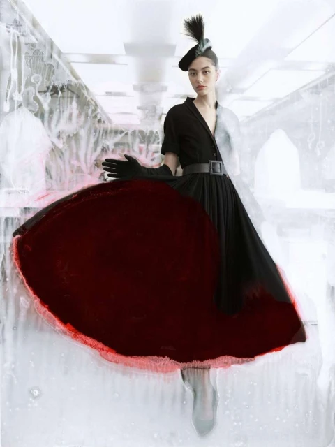 A woman in a black dress and matching hat poses with one arm raised against a white background featuring abstract structural elements.