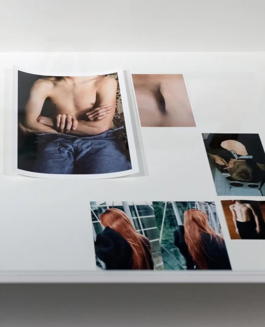 Display of art photographs on a white surface featuring male and female torsos, and portrait shots with red hair.