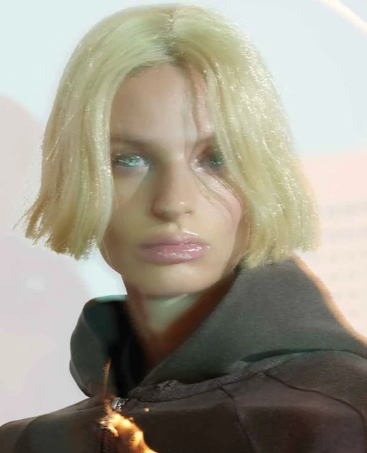 Close-up of a woman with blonde hair wearing a grey hoodie, capturing beauty and fashion in a brightly lit indoor setting.