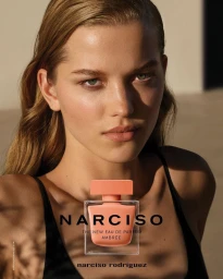 Close-up portrait of a young woman with freckles and light brown hair next to a perfume bottle by Viviane Sassen